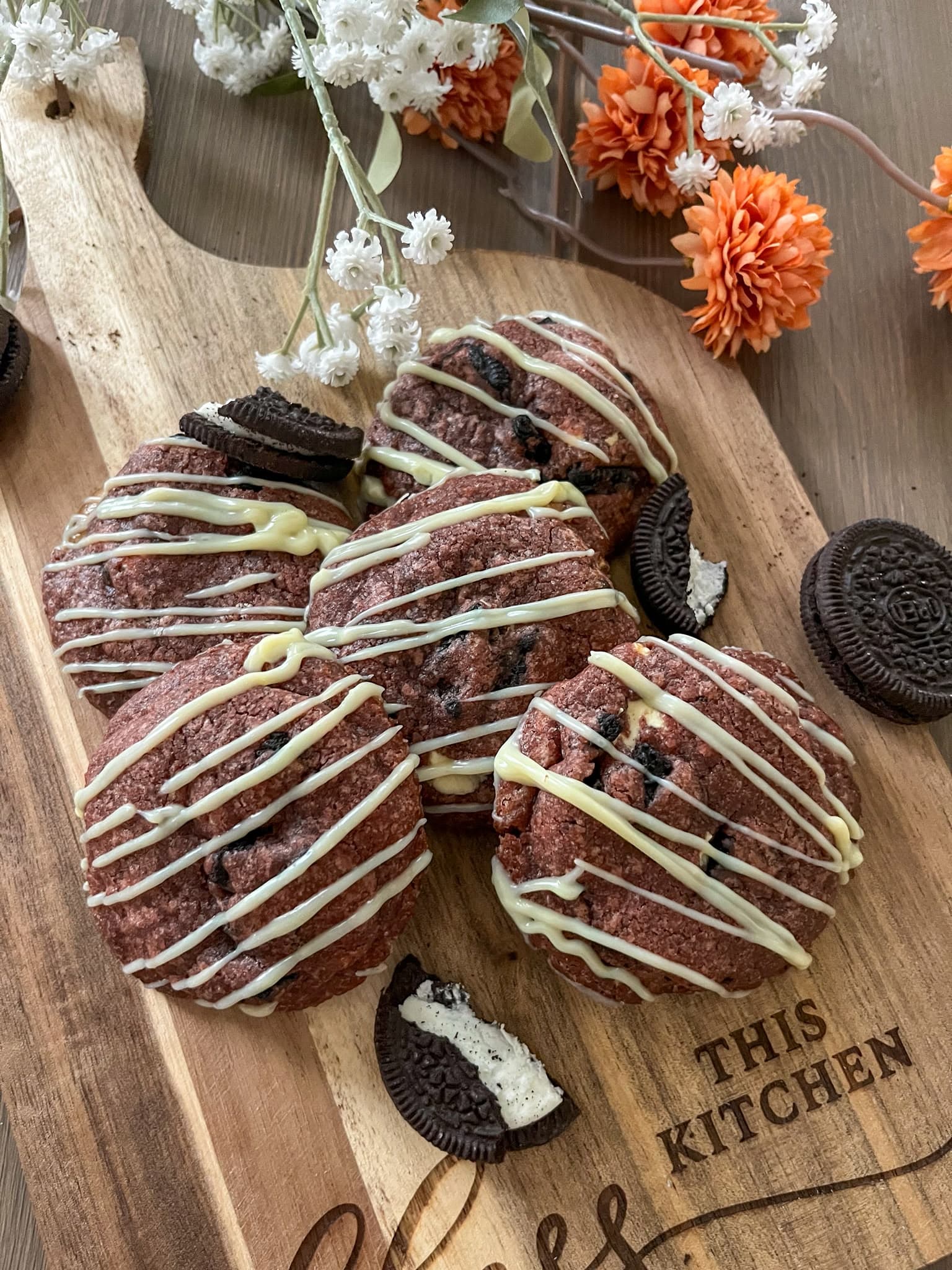 Red velvet cookies met witte chocolade op een houten plank, met stukjes koekje ernaast